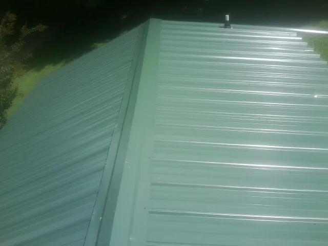 New green metal panels meeting at the ridge of a roof — Flat Roof Repair work by our crew in Victoria