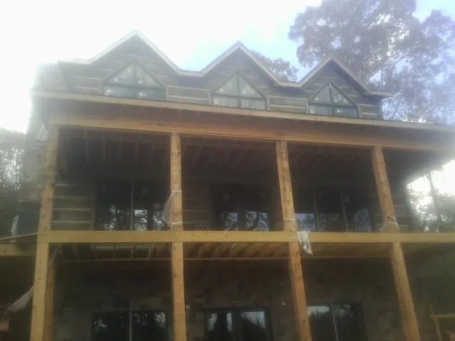 Dormers and porch framing on a large log home under construction — Roof Coating work by our crew in Victoria