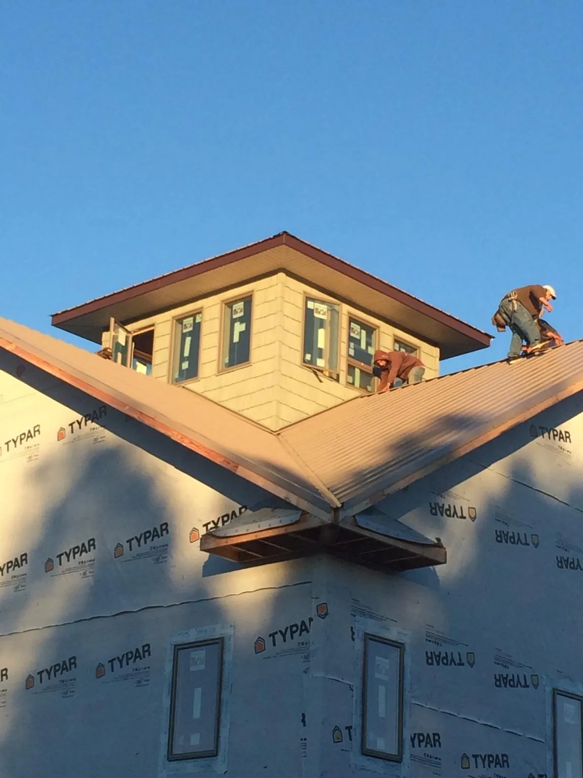 Roofers working around a rooftop cupola on a new metal roof at sunset — Roof Waterproofing in Victoria by Roofing Brothers